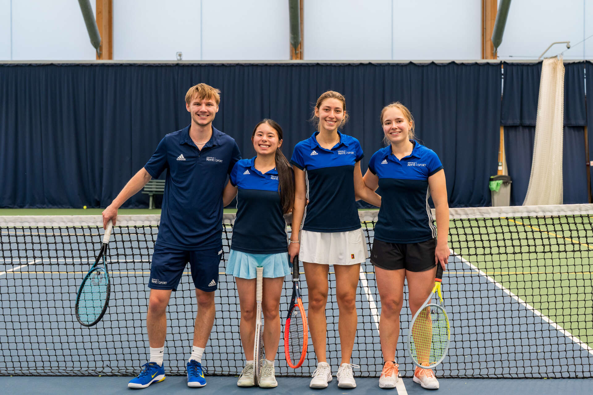 Student tennis coaches smiling and holding tennis rackets