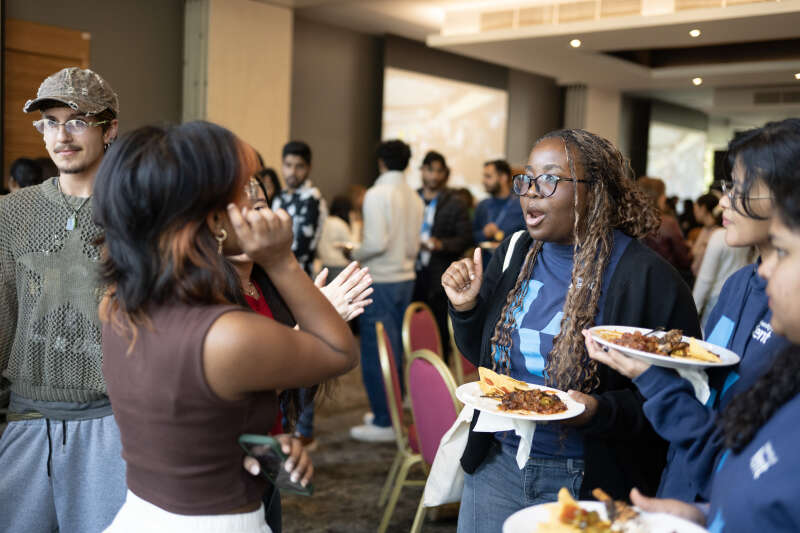 A group of students at an event, chatting and eating food.