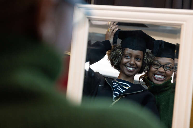 A photo of two students at their graduation that someone else is looking at.