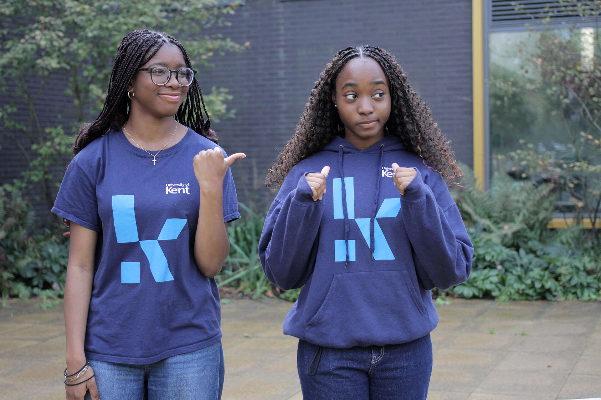 ResLife Ambassadors Tabi and Ike in blue Kent branded tshirt and hoodie posing together outside our Kennedy building.