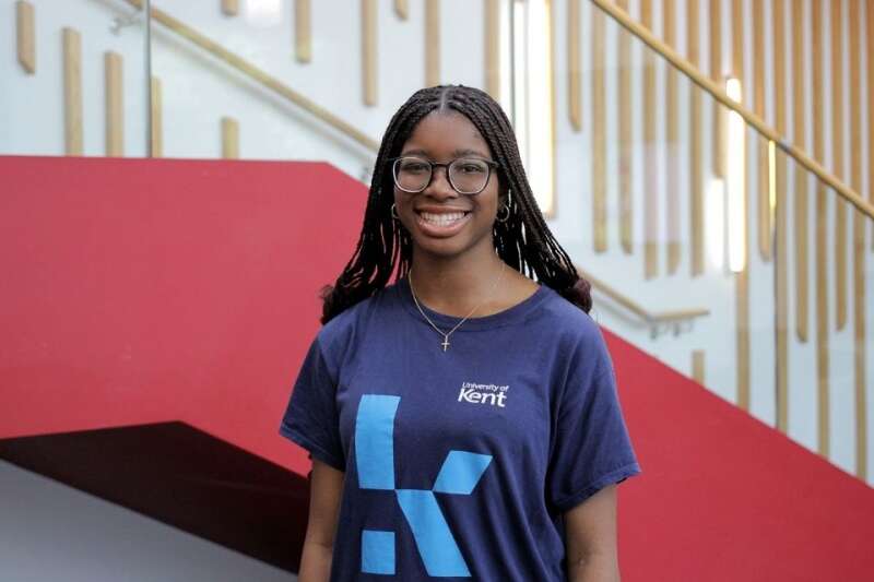 Tabi in a blue Kent branded t-shirt, posing by the stairs in our Kennedy building.