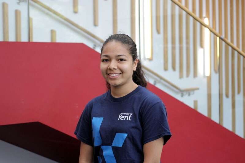 Mardhiah in a blue Kent branded t-shirt, posing by the stairs in our Kennedy building.