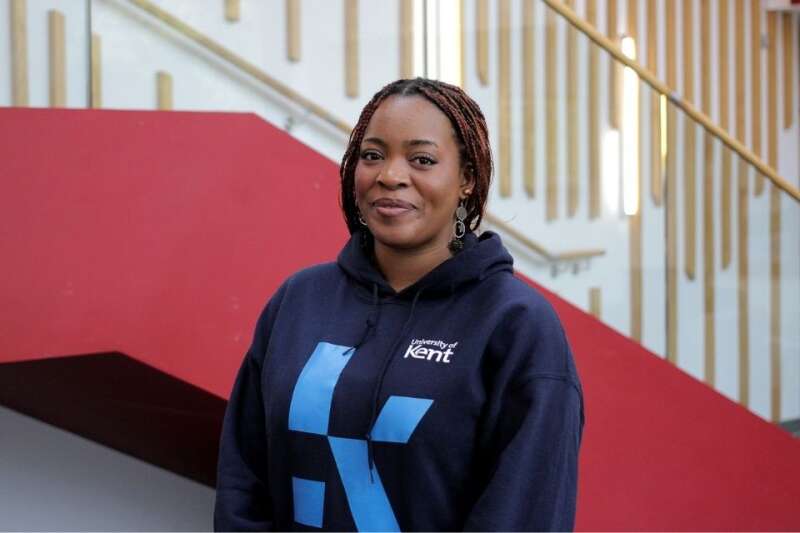 Stephanie in a blue Kent branded hoodie, posing by the stairs in our Kennedy building.