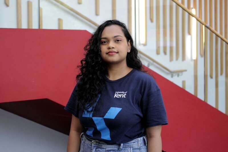 Mishti in a blue Kent branded t-shirt, posing by the stairs in our Kennedy building.