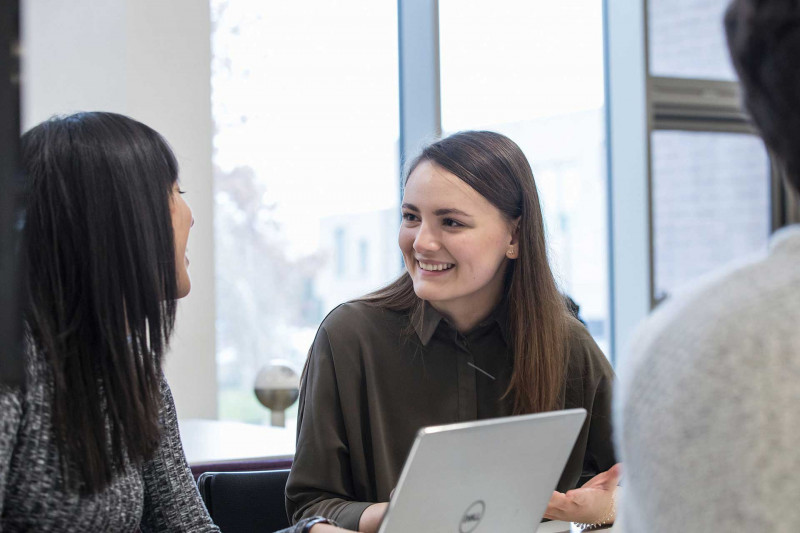 Students sitting in front of a laptop discussing their work