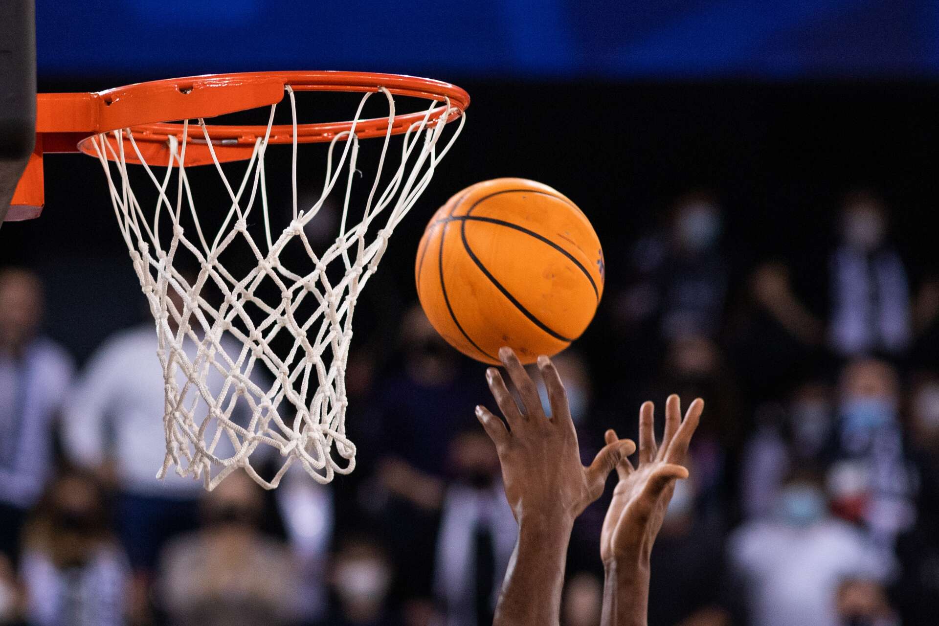 A basketball player in a red jersey shoots a layup during a competitive game on an indoor court at Kent Sport.