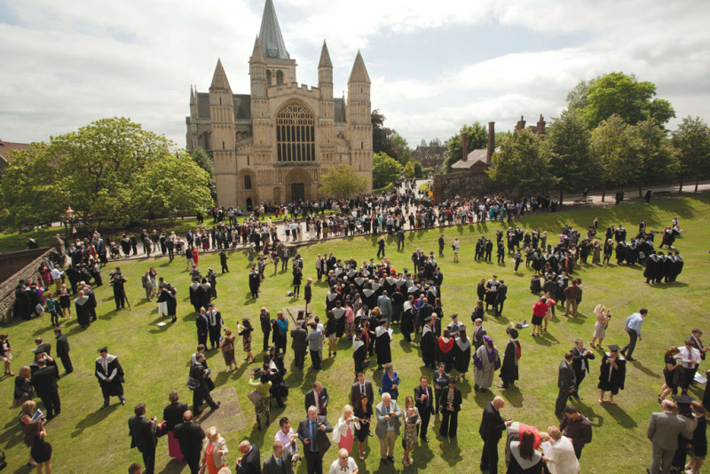 Gathering of people on lawn outside cathedral.