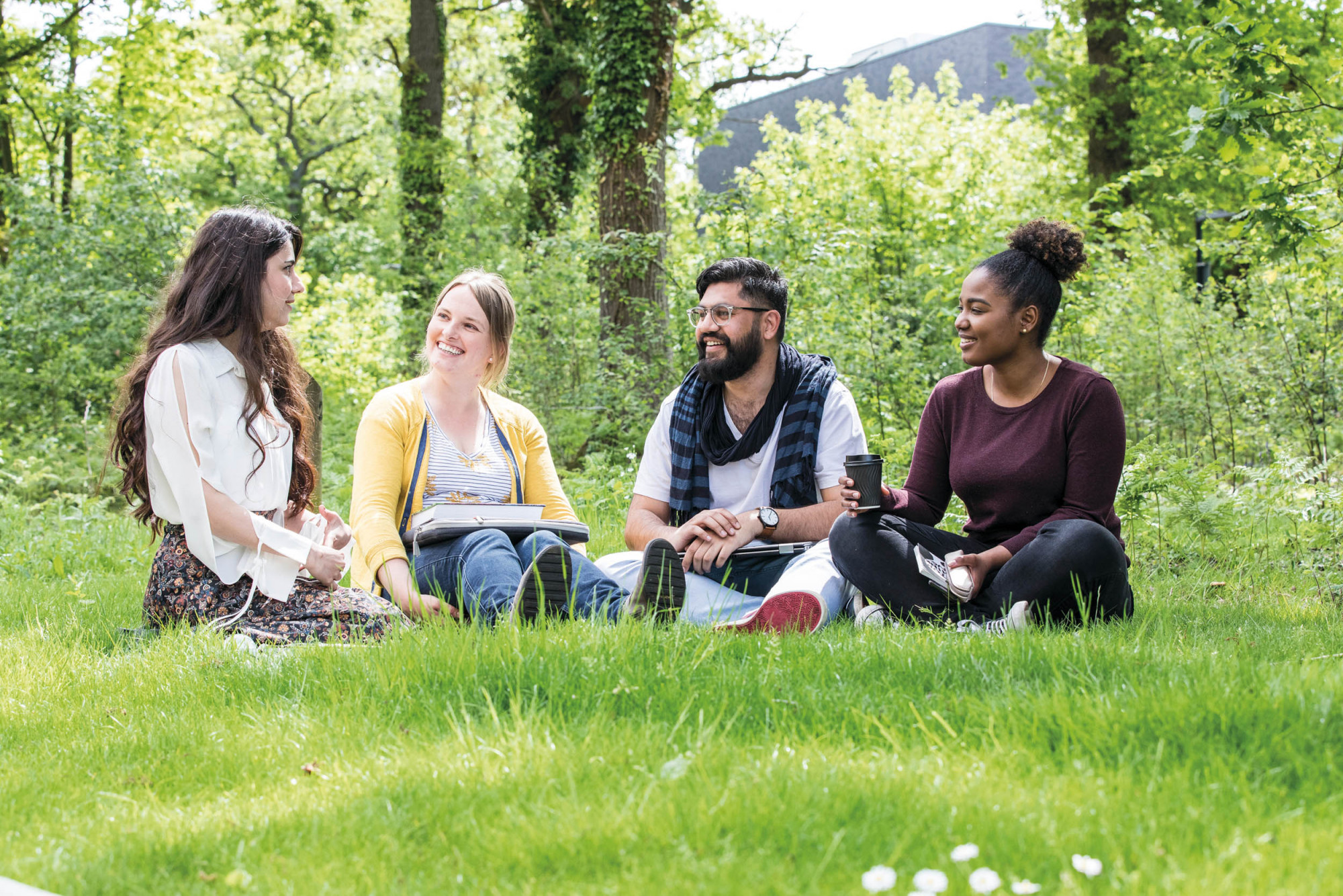 University of Kent students talking while sat in outside on grass