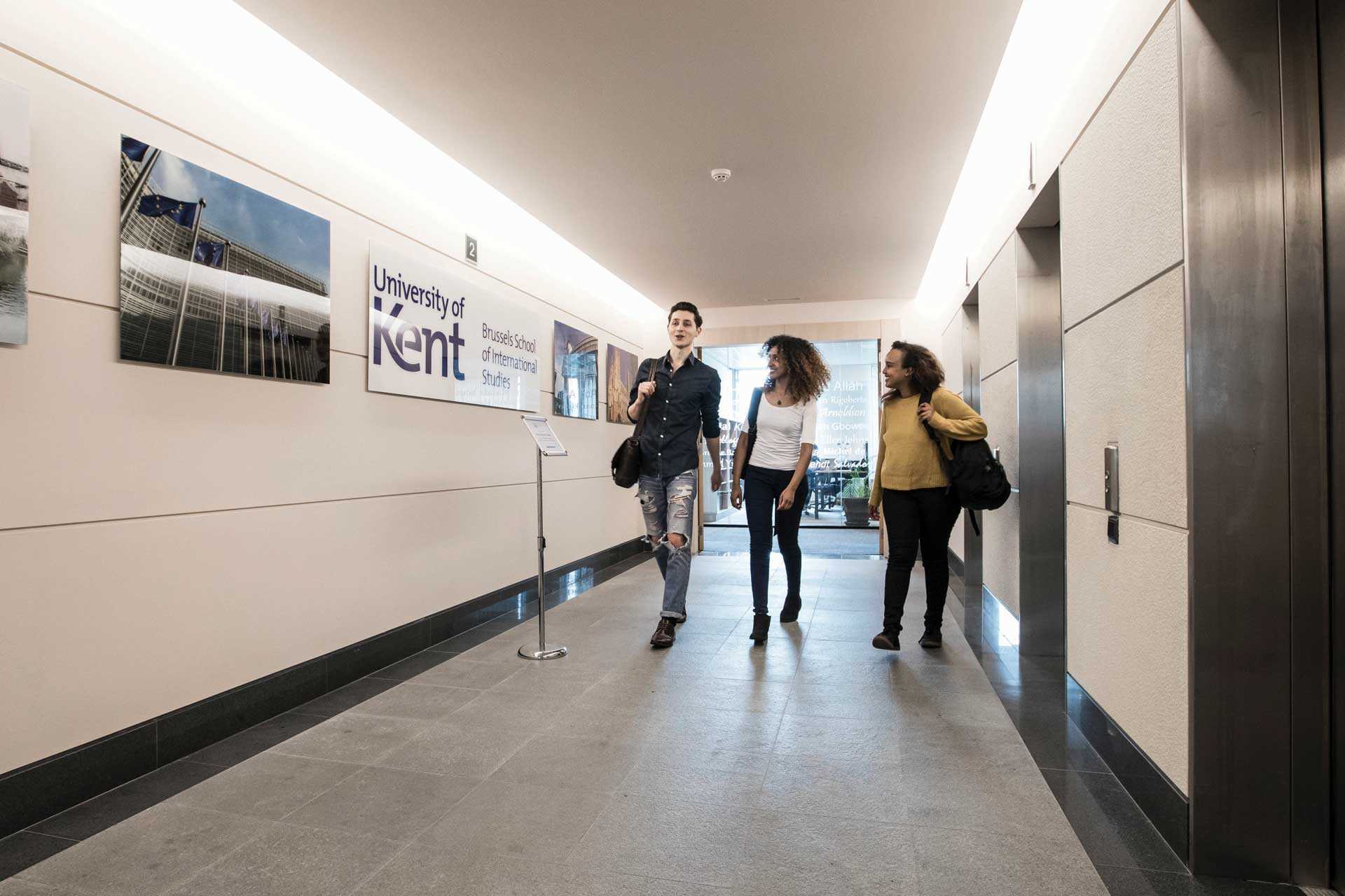 Three students walk down a corridor in Brussels School of International Studies