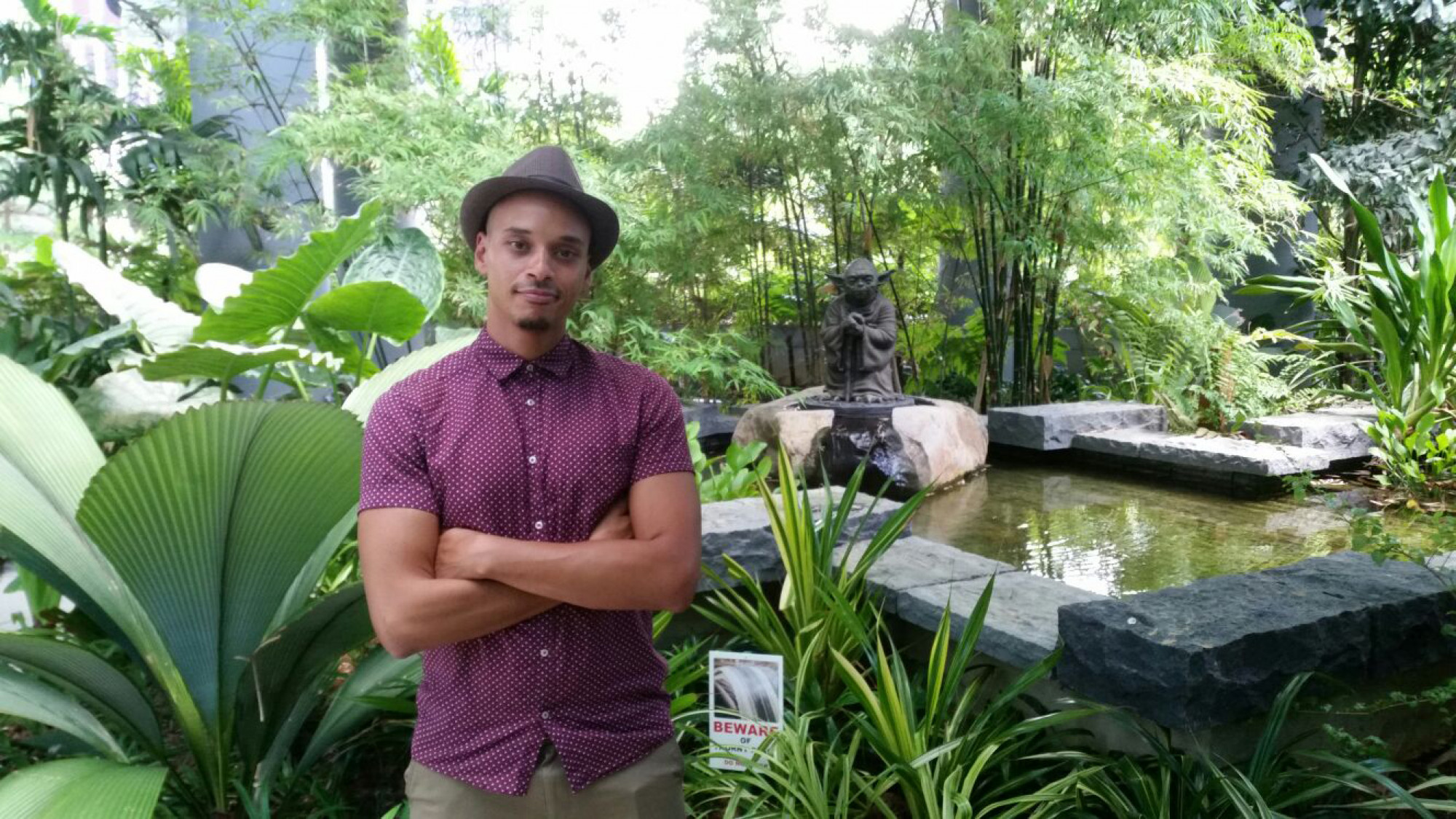 El Suliman standing in front of a pond and statue of Yoda