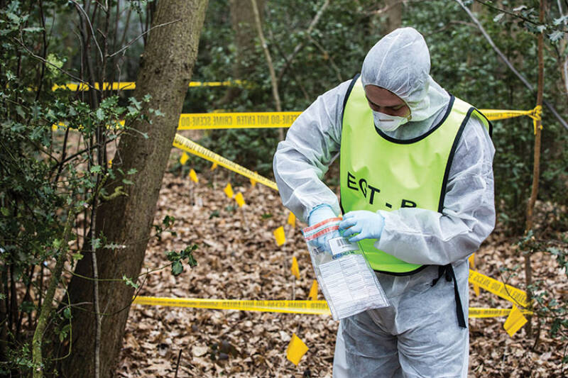 Student in white coveralls working on a crime scene