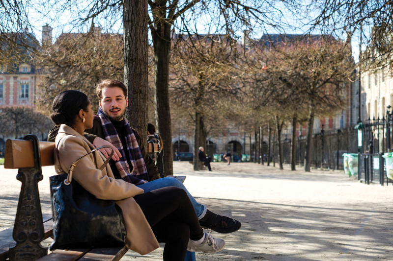 Two students talking on a bench in a park in Paris