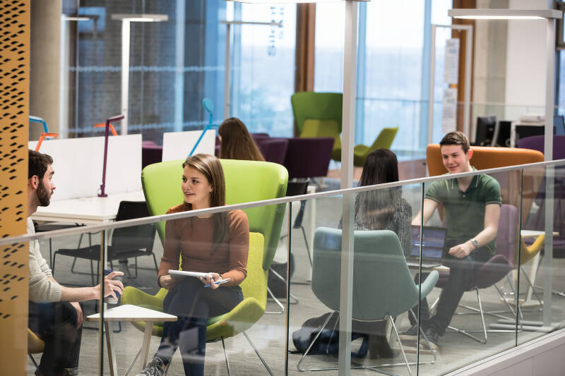 People on informal seating and using reading desks in the Templeman Library