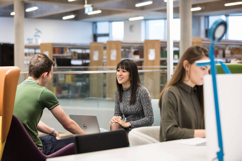 Students chatting on informal seating and using reading desks in the Templeman Library