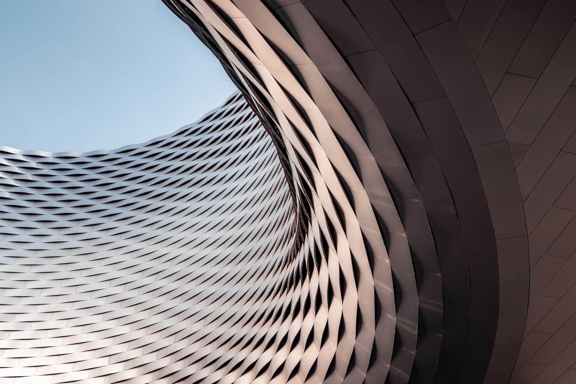 part of a curved building, swooping round against a blue sky