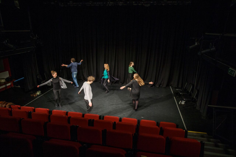 A group of students perform on stage in an empty theatre