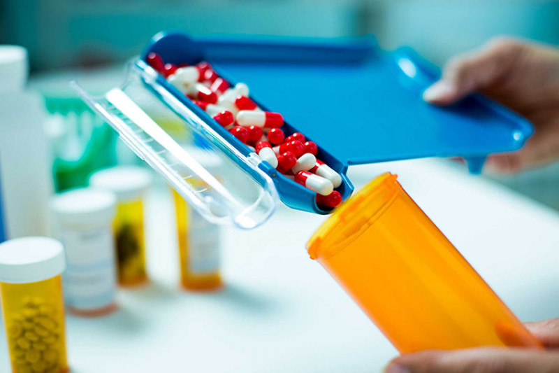 Pharmacy pours red and white tablets into a tube