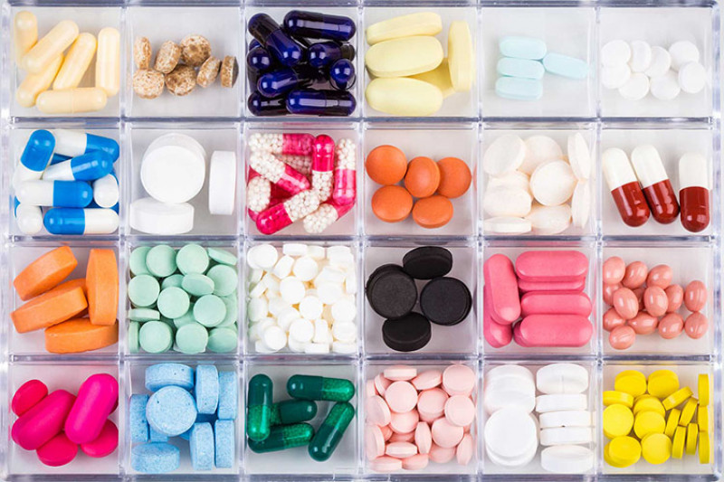 Tray of multi-coloured pills and tablets organised into square compartments