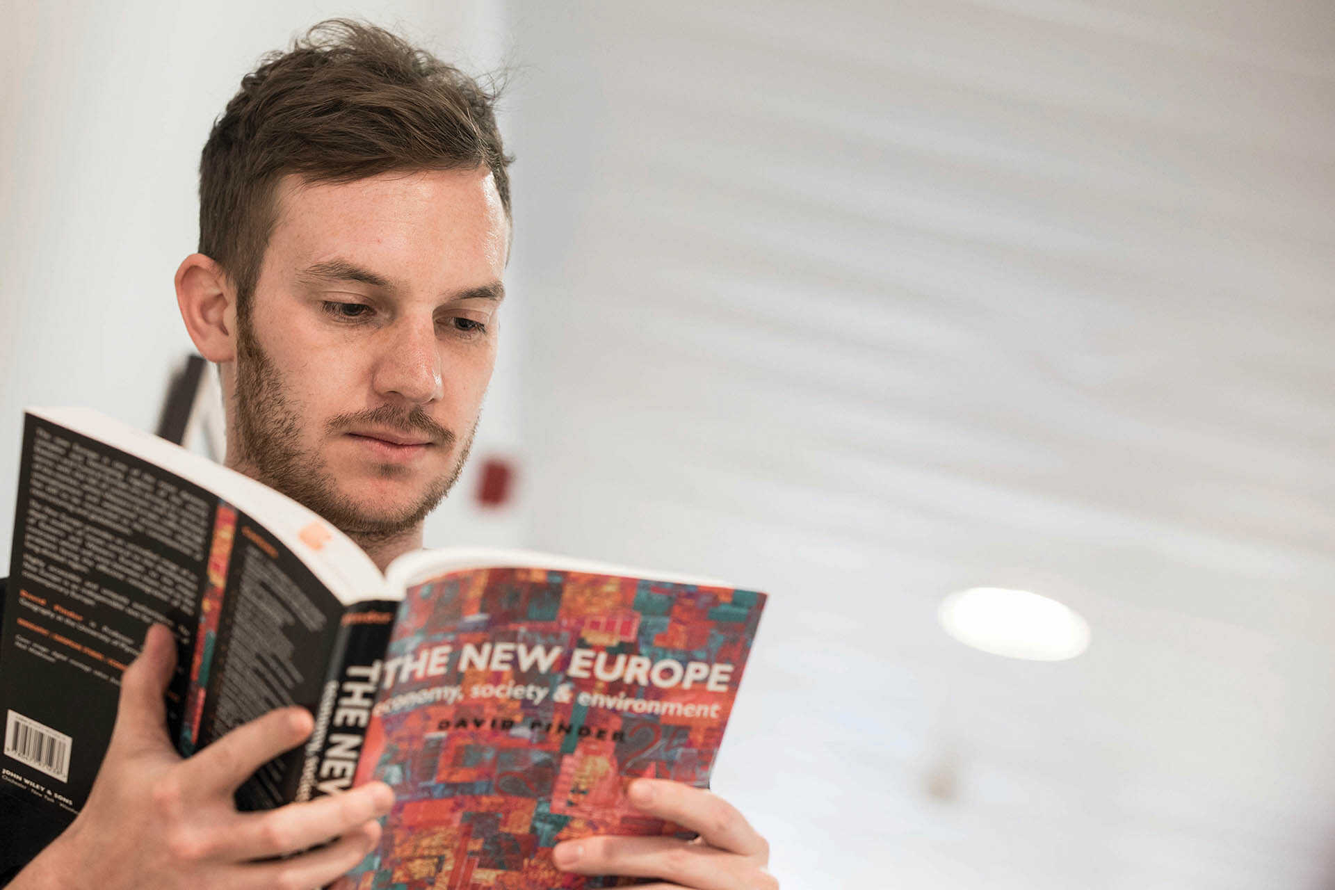 Research student reads a paperback copy of The New Europe