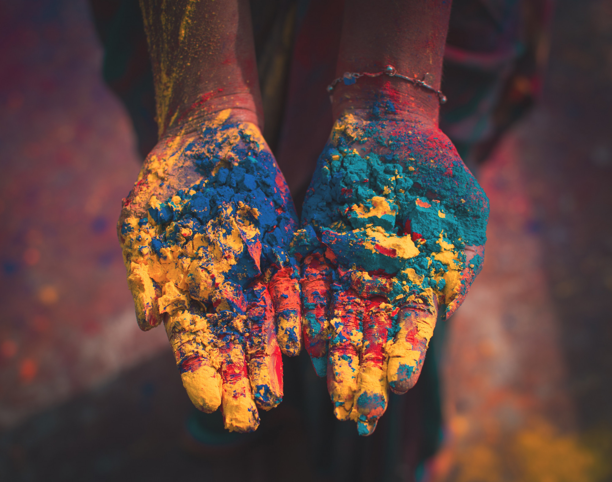 A pair of outstretched hands hold brightly coloured powder at Holi