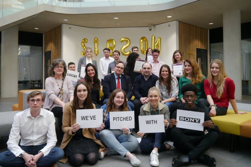 Students sat in a group holding up signs saying "We've pitched with Sony"