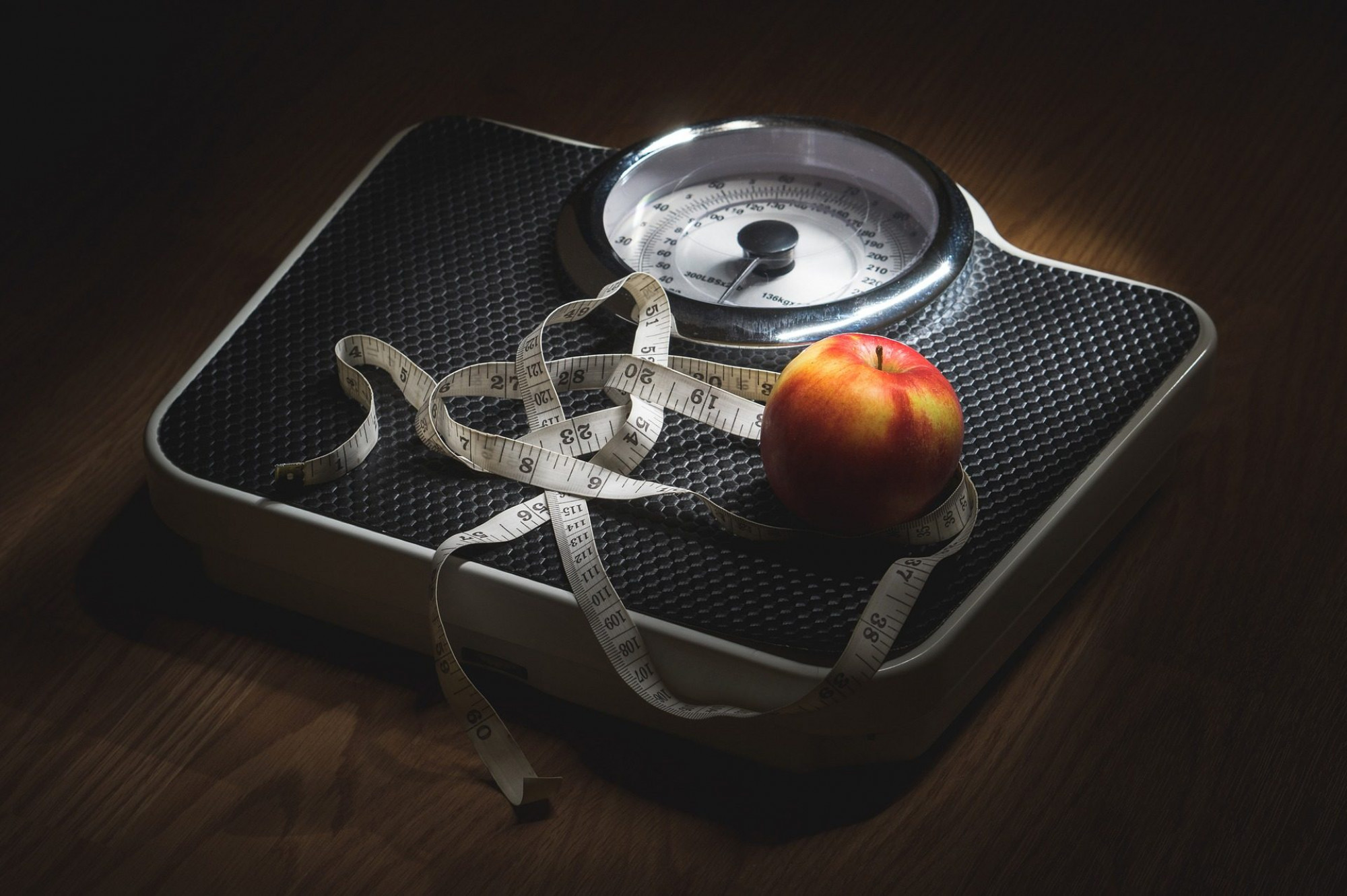 Weighing scales with measuring tape and apple