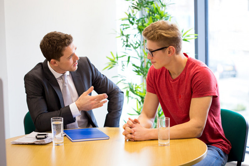 Male lecturer speaking to male student in an interview