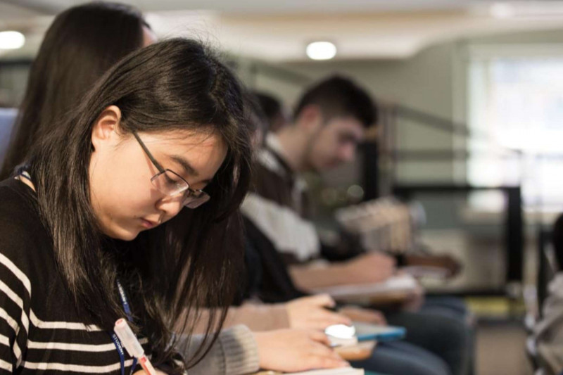 Line of students making notes in a lecture theatre
