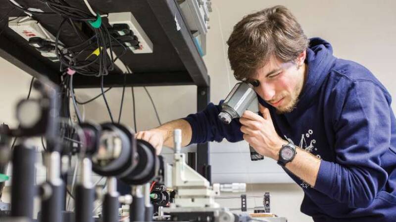 Male postgrad student carrying out experiment using optical instruments