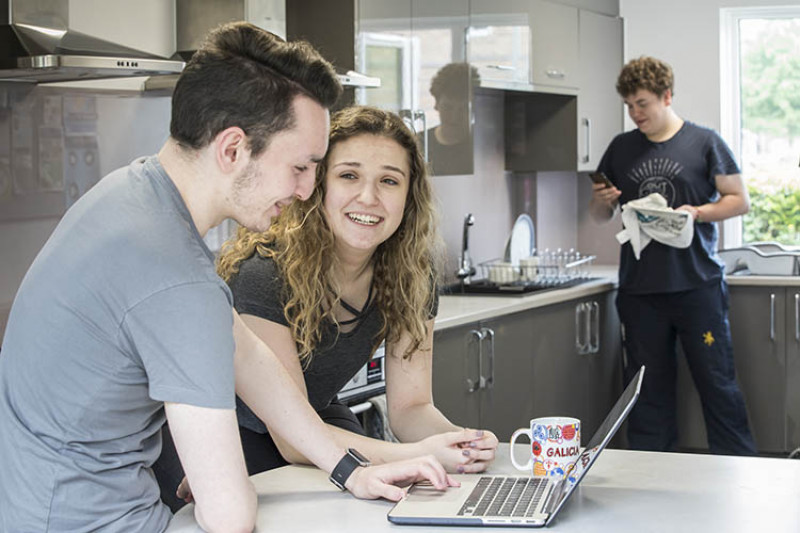 Students in Park Wood House kitchen talking and working on laptop