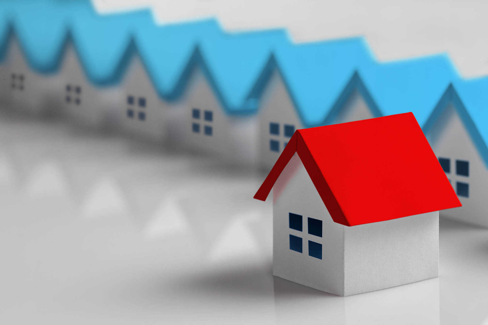 House with red roof in front of row of blue-roofed houses