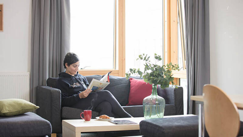 Female student reading a magazine in the living area of Woolf College