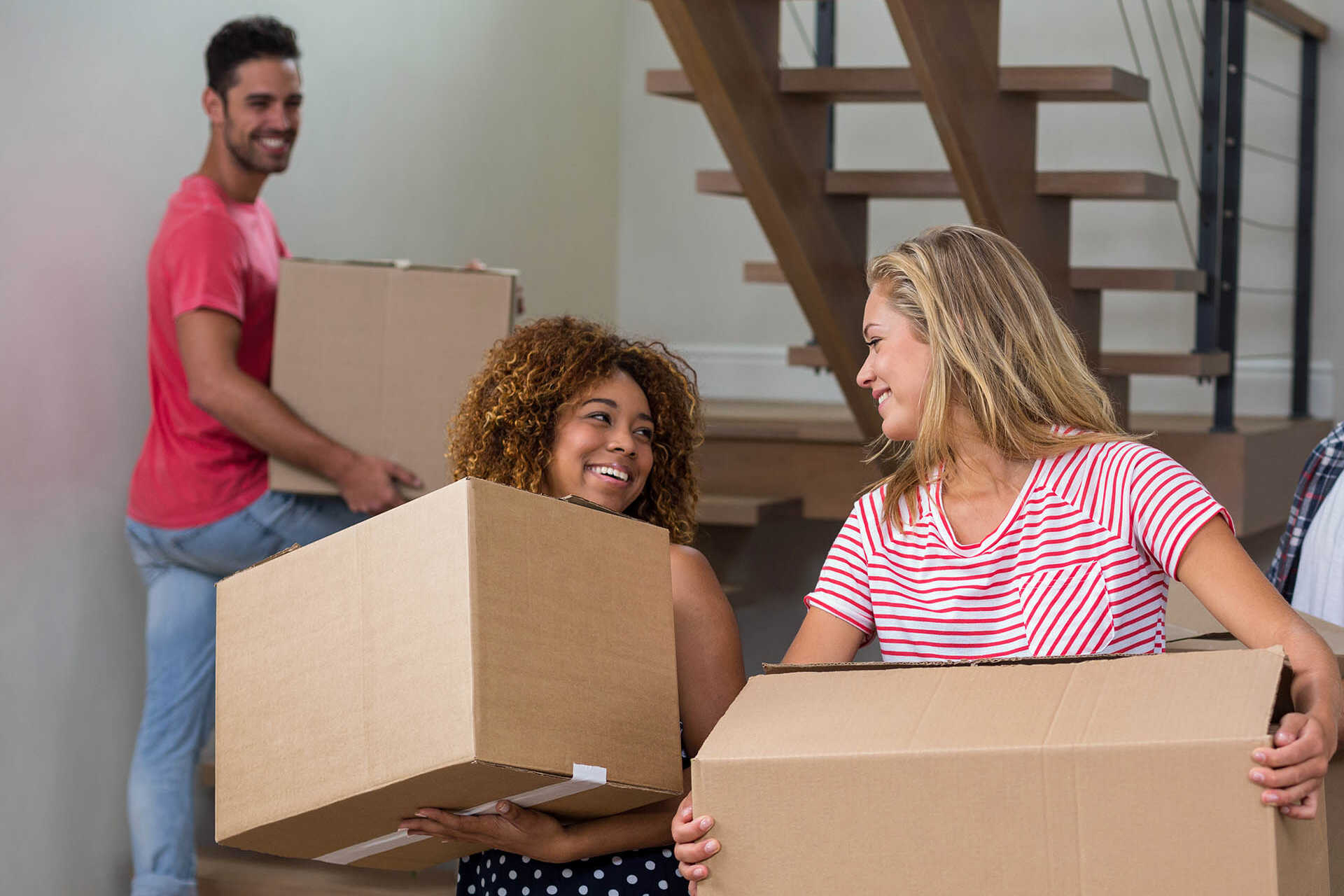 A group of students carry boxes into their new house