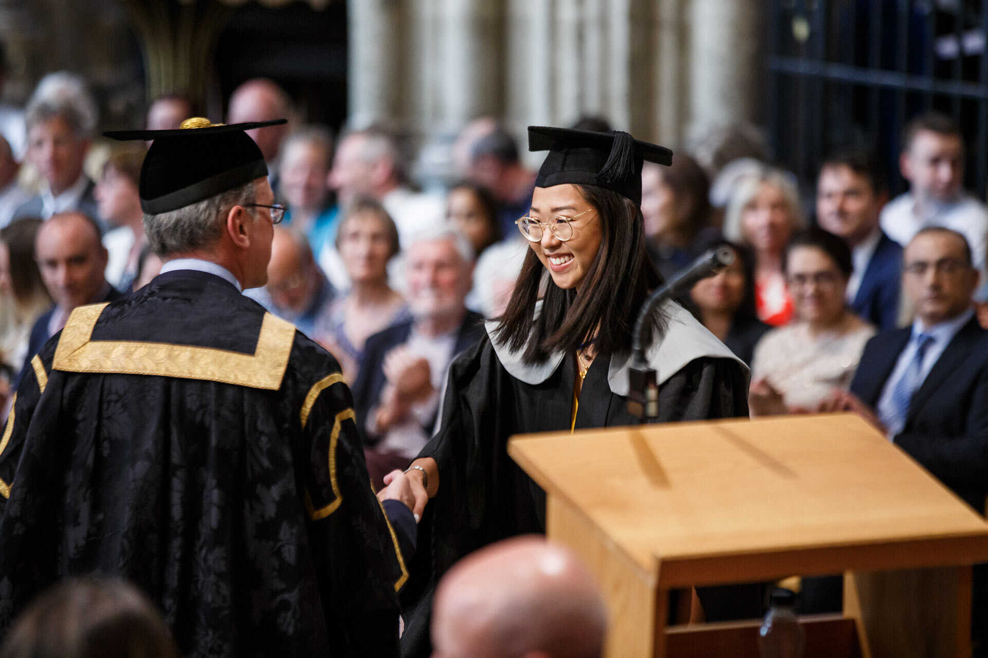 A smiling student graduating their degree in Canterbury Cathedral