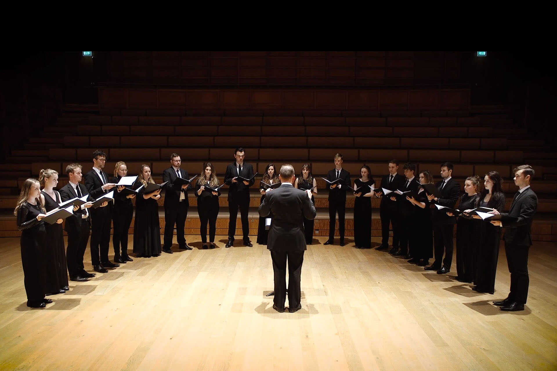 Choir standing in a semi-circle facing a conductor