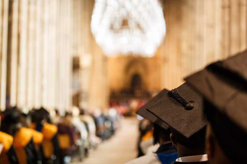 decorative image only - displaying the Cathedral nave blurred and graduation caps in focus